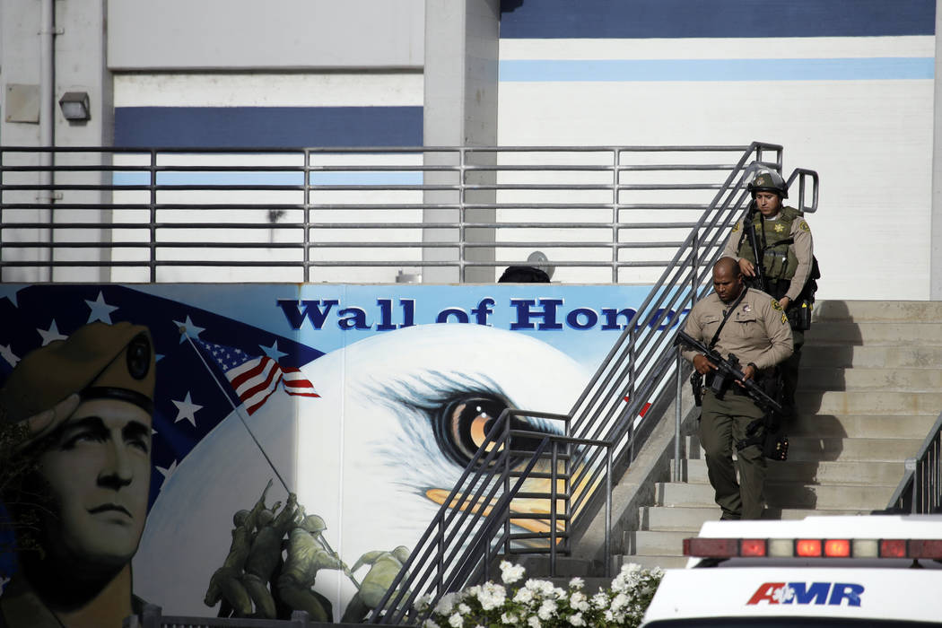 Law enforcement personnel walk with their weapons drawn outside of Saugus High School after rep ...