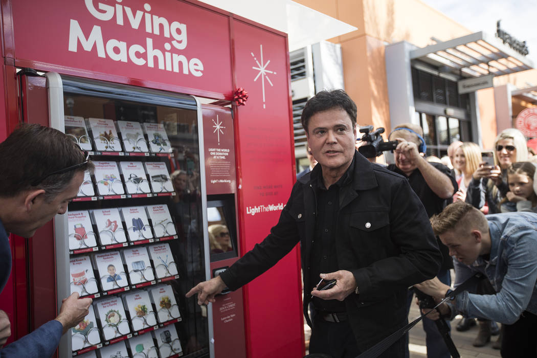 Donny Osmond purchases from the Giving Machine, a vending machine that offers different items f ...