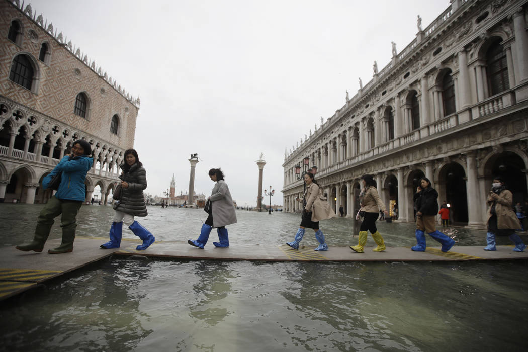 People use trestle bridges to walk in a flooded St. Mark's Square at Venice, Friday, Nov. 15, 2 ...