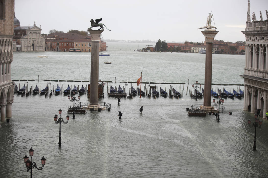 People make their way in a flooded St. Mark's Square in Venice, Italy, Friday, Nov. 15, 2019. ...