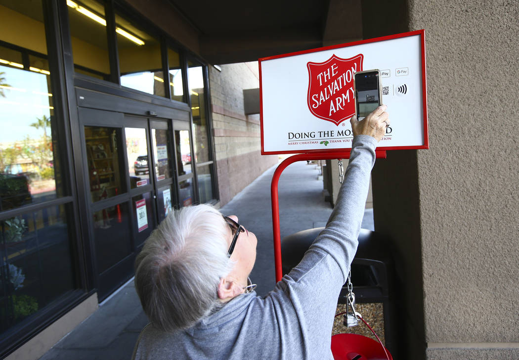 Leslee Rogers, of The Salvation Army, demonstrates how to donate with mobil phone outside of Ho ...