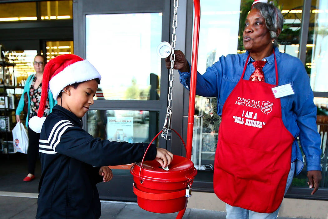 Christopher Torres, 9, donates money as The Salvation Army bell ringer Earline Scott, right, ri ...