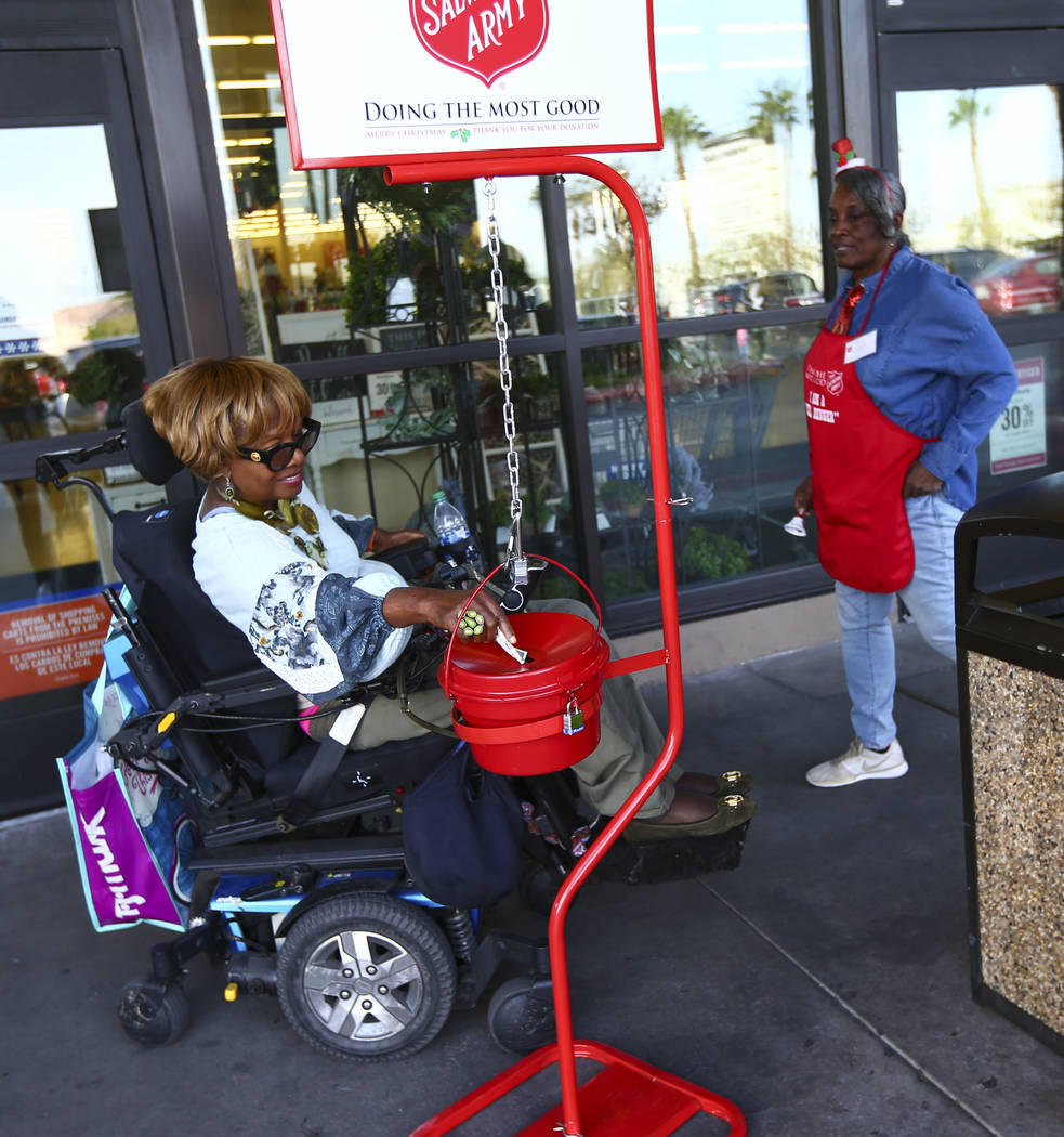 Patricia Collins puts money in the The Salvation Army red kettle as bell ringer Earline Scott, ...