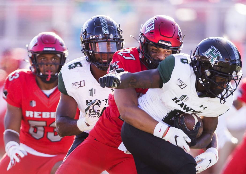 UNLV Rebels linebacker Austin Ajiake (27) tackles Hawaii Warriors wide receiver Cedric Byrd II ...