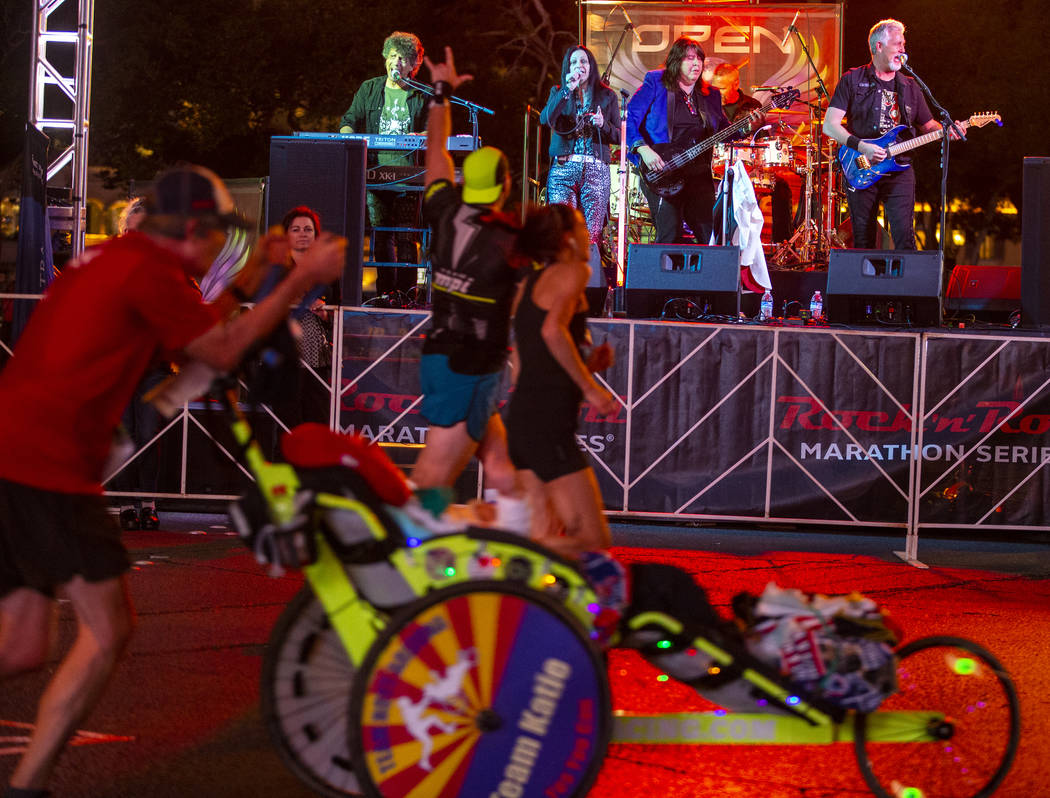 Runners listen as they pass the Open Arms Journey Tribute band during the Las Vegas Rock 'n' Ro ...
