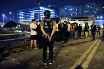 A riot policeman watches over a group of detained people on a bridge in Hong Kong, early Tuesda ...