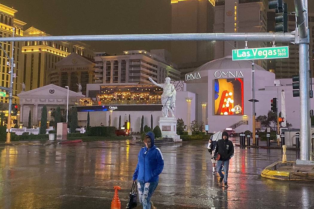 Pedestrians cross the Las Vegas Strip near Caesars Palace in the rain, Wednesday, Nov. 20, 2019 ...