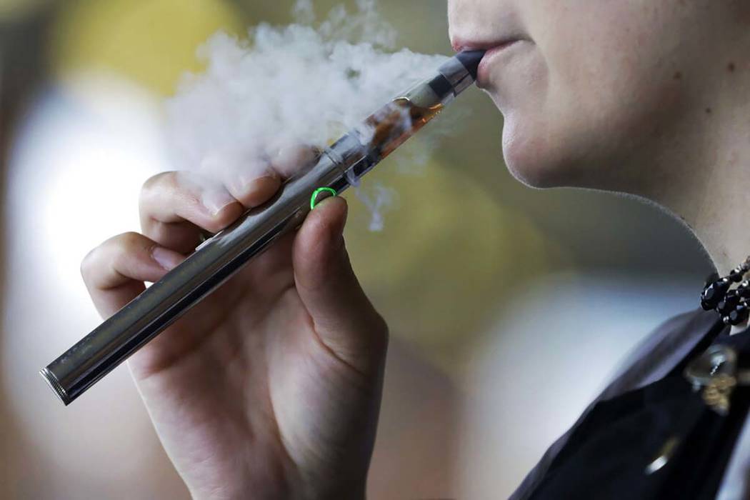 In an Oct. 4, 2019, file photo, a woman using an electronic cigarette exhales in Mayfield Heigh ...