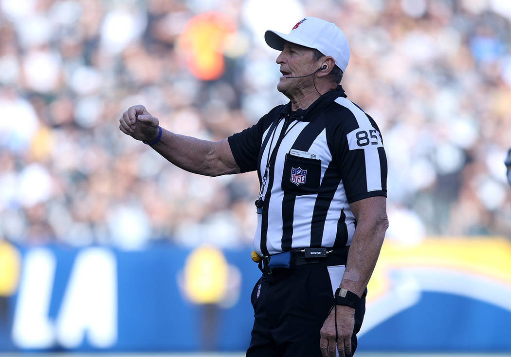 Referee Ed Hochuli (85) announces a penalty to the crowd during the first half of a NFL game be ...