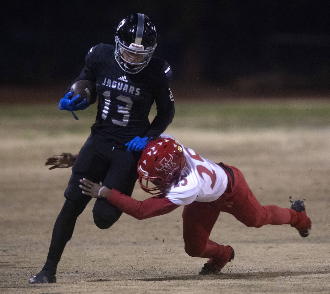 Desert Pines' Michael Jackson (13) runs with the ball as Arbor View's Adrian Bates (25) jumps t ...