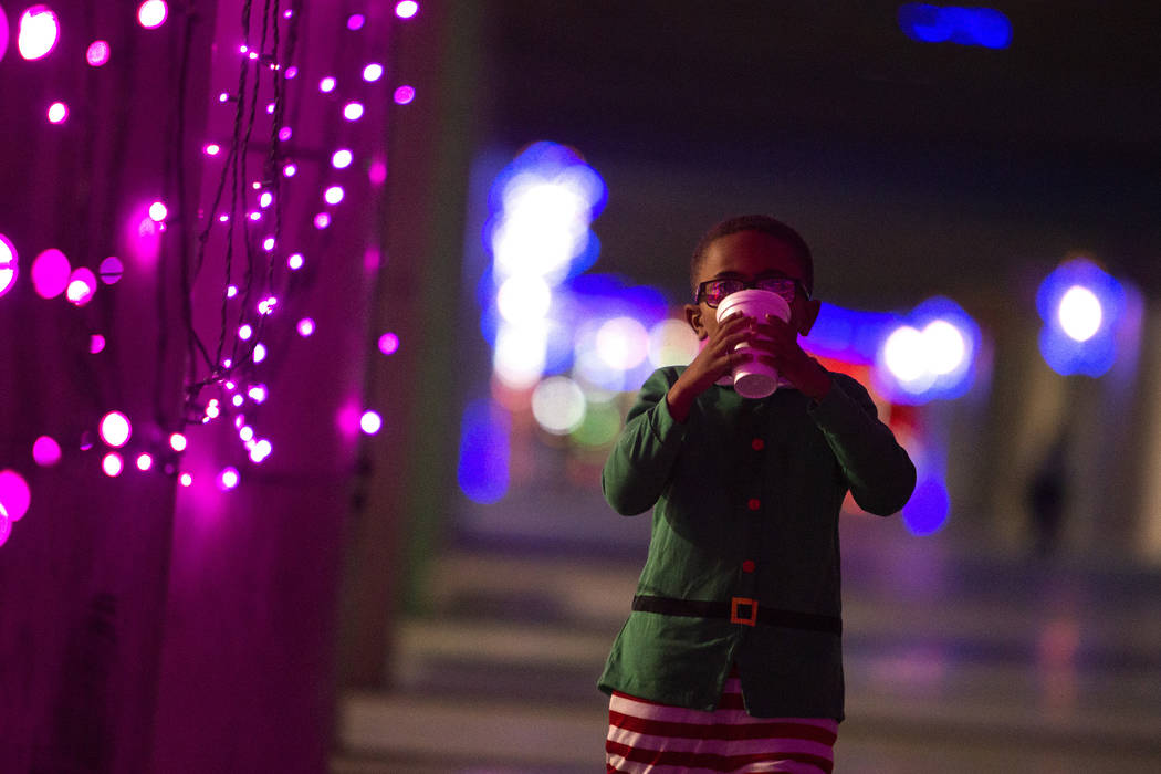 Noah Joe, 5, of Las Vegas, sips hot cocoa as he walks through Glittering Lights at the PJ 5K &a ...