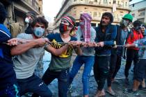 Demonstrators try to pull down concrete walls placed by Iraqi security forces to close in the h ...