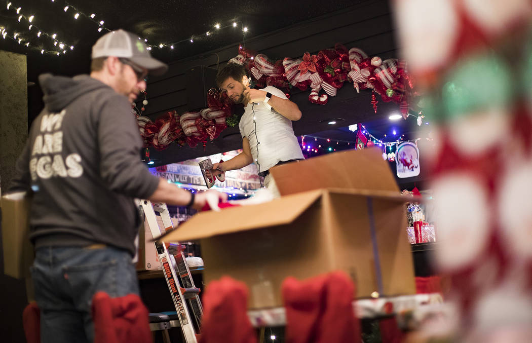 Garrett Pattiani, center, co-owner of Bright Light Holiday Company, works to hang lights at the ...