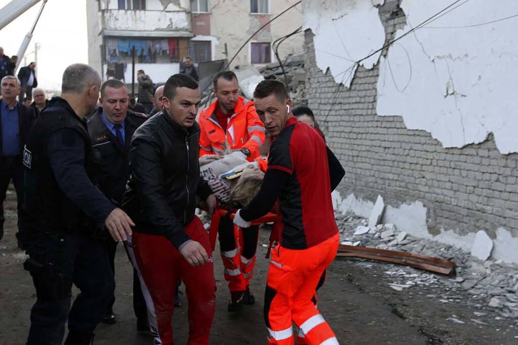 Rescuers carry an injured woman after a magnitude 6.4 earthquake in Thumane, western Albania, T ...