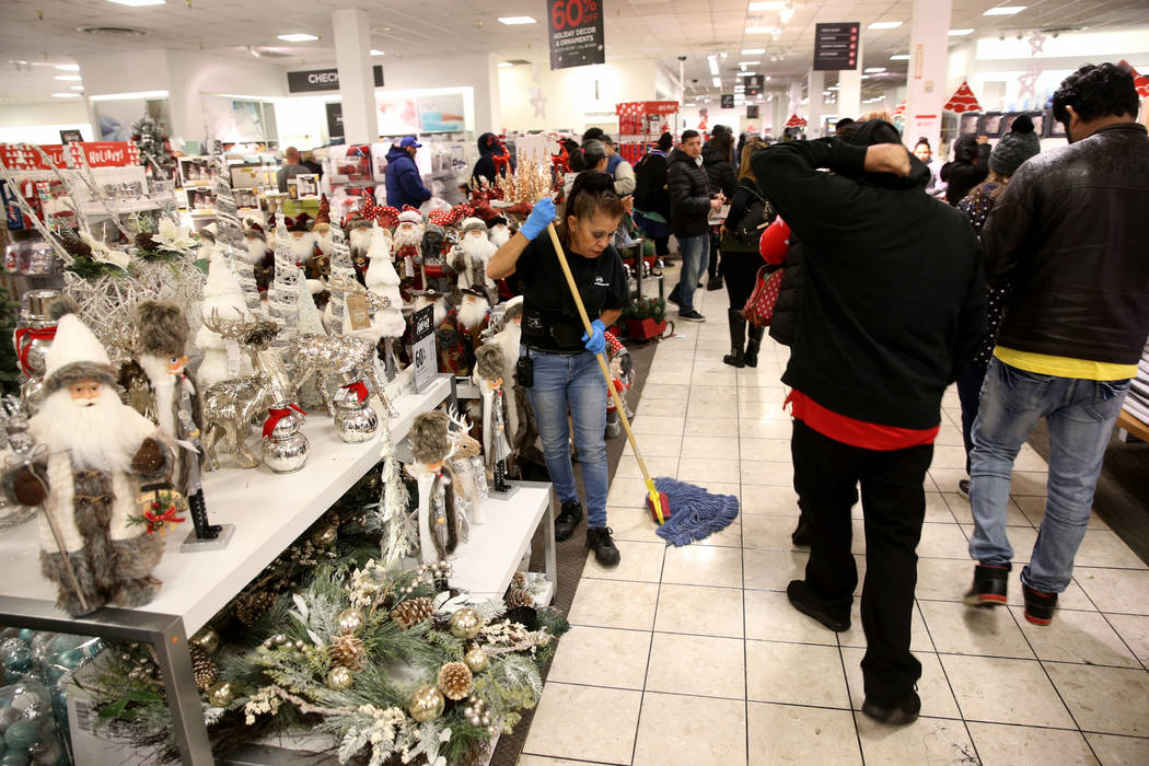 Imelda Alvarez keeps the floor dry as wet shoppers look for early Black Friday deals at JCPenny ...