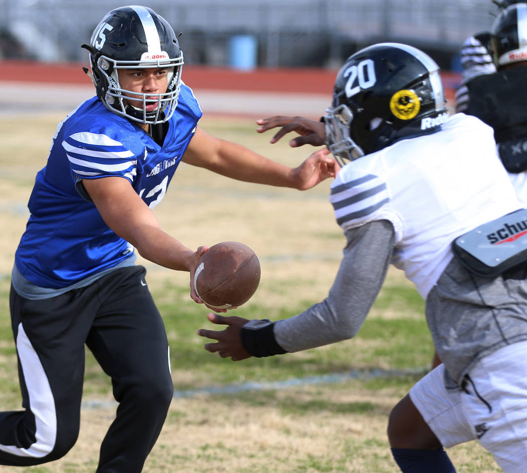 Desert Pines' Rjay Tagataese (15) hands off the ball to DeAvonte McGee (20) for a run during a ...