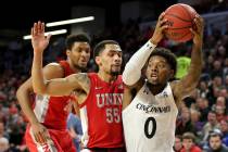 Cincinnati guard Chris McNeal (0) drives to the basket as UNLV guard Elijah Mitrou-Long (55) de ...