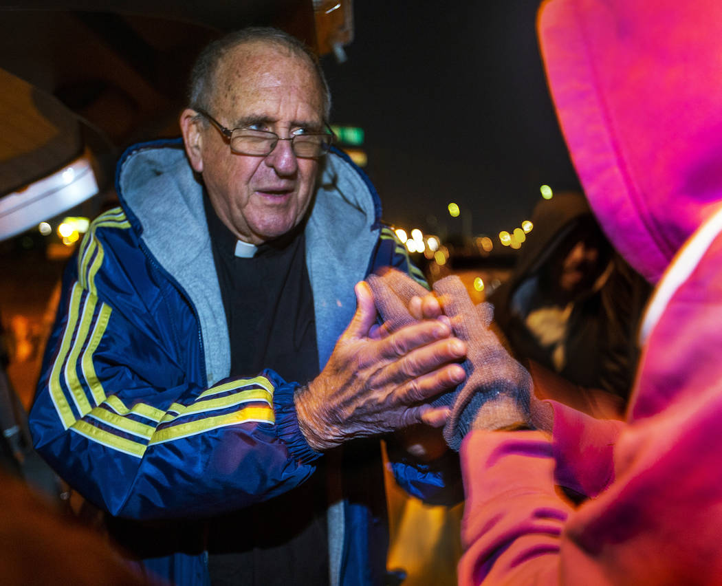 Father John McShane says a prayer for a woman in need during Giving Back Mondays on G Street an ...