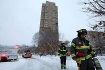 Minneapolis firefighters leave after a deadly fire at a high-rise apartment building, in backgr ...