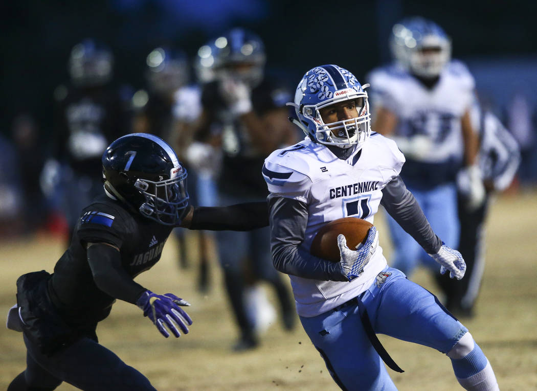 Centennial's Aaron Shields (7) runs the ball past Desert Pines' Darrien Stewart (7) during the ...