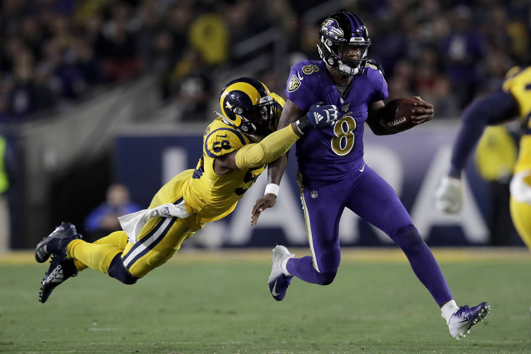 Baltimore Ravens quarterback Lamar Jackson, right, is tackled by Los Angeles Rams defensive end ...