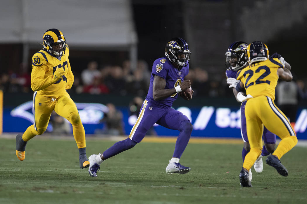 Baltimore Ravens quarterback Lamar Jackson, center, sprints as Los Angeles Rams defensive end M ...