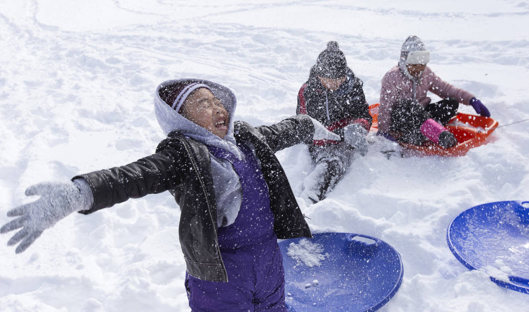 Matthew Pham, 4, of Las Vegas, left, throws snow into the air while sledding with his brother M ...