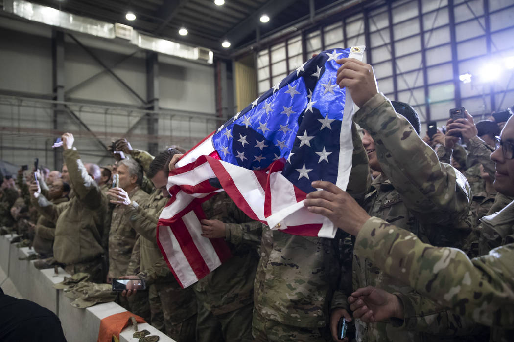 Members of the military unfurl an American flag as President Donald Trump speaks during a surpr ...