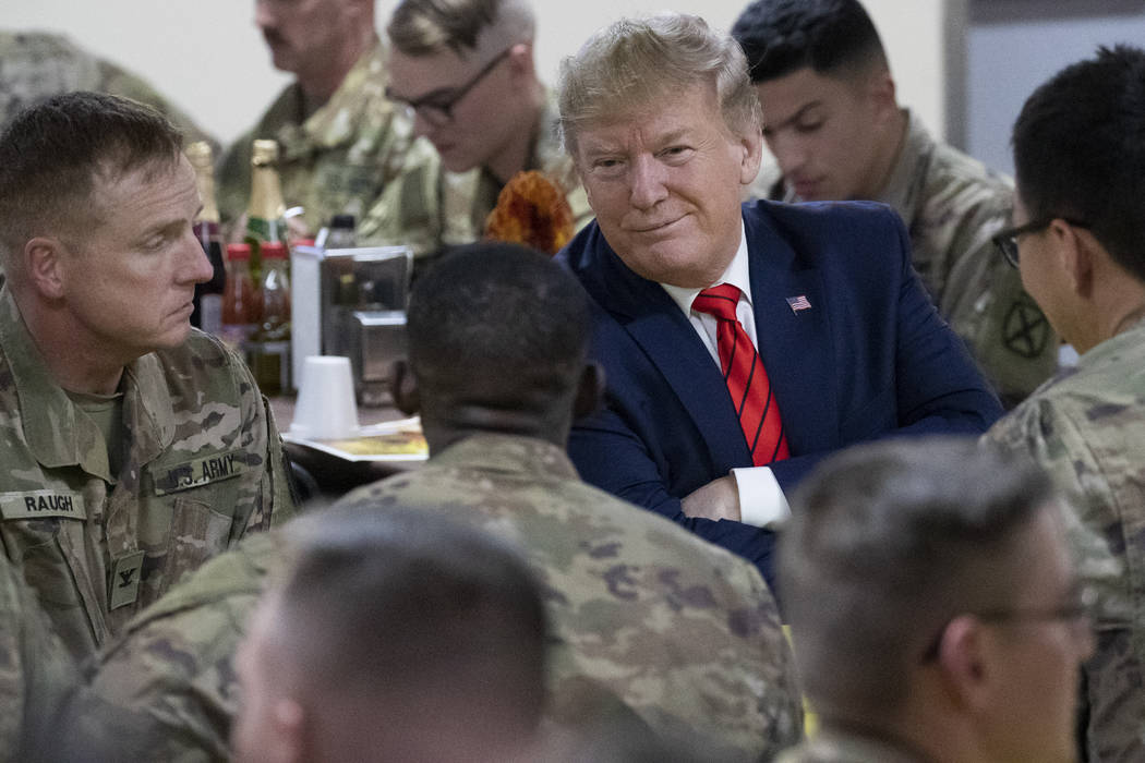 President Donald Trump smiles while sitting with the troops during a surprise Thanksgiving Day ...