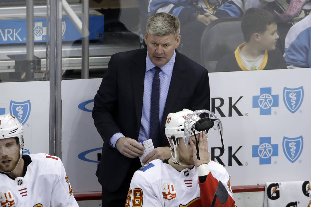 Calgary Flames head coach Bill Peters stands behind Andrew Mangiapane (88) during the third per ...