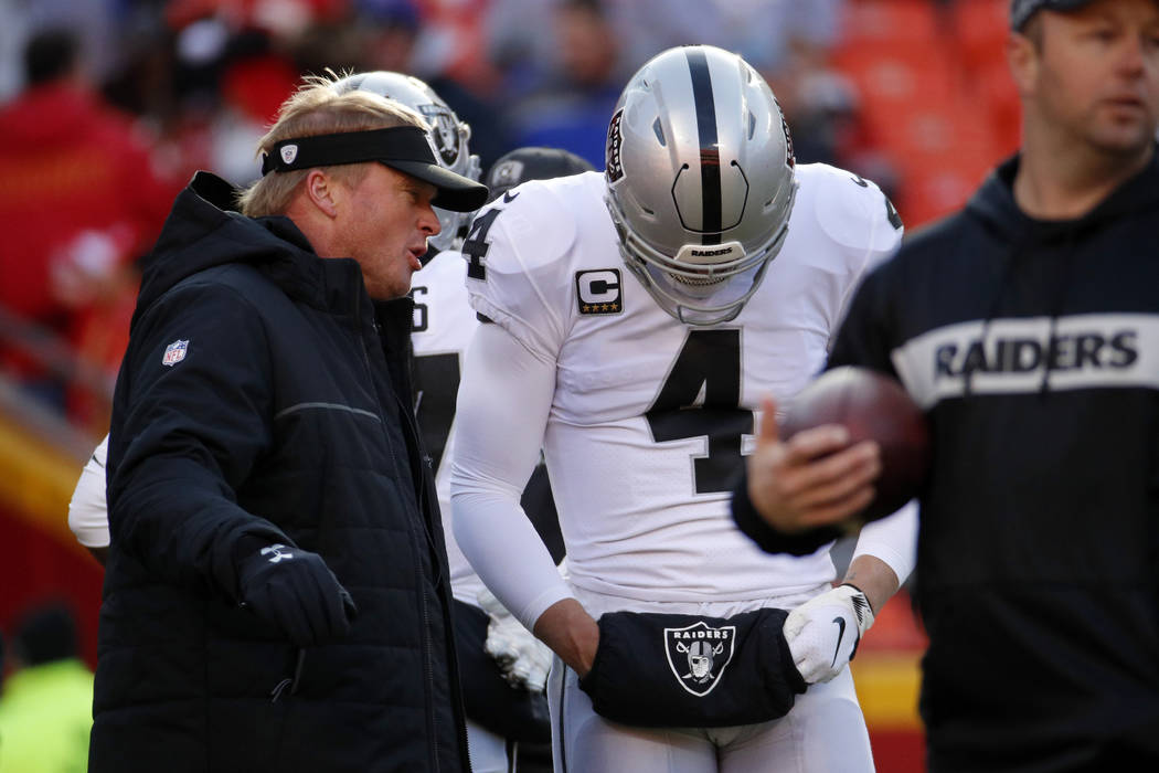 Oakland Raiders head coach Jon Gruden talks to quarterback Derek Carr (4) before an NFL footbal ...