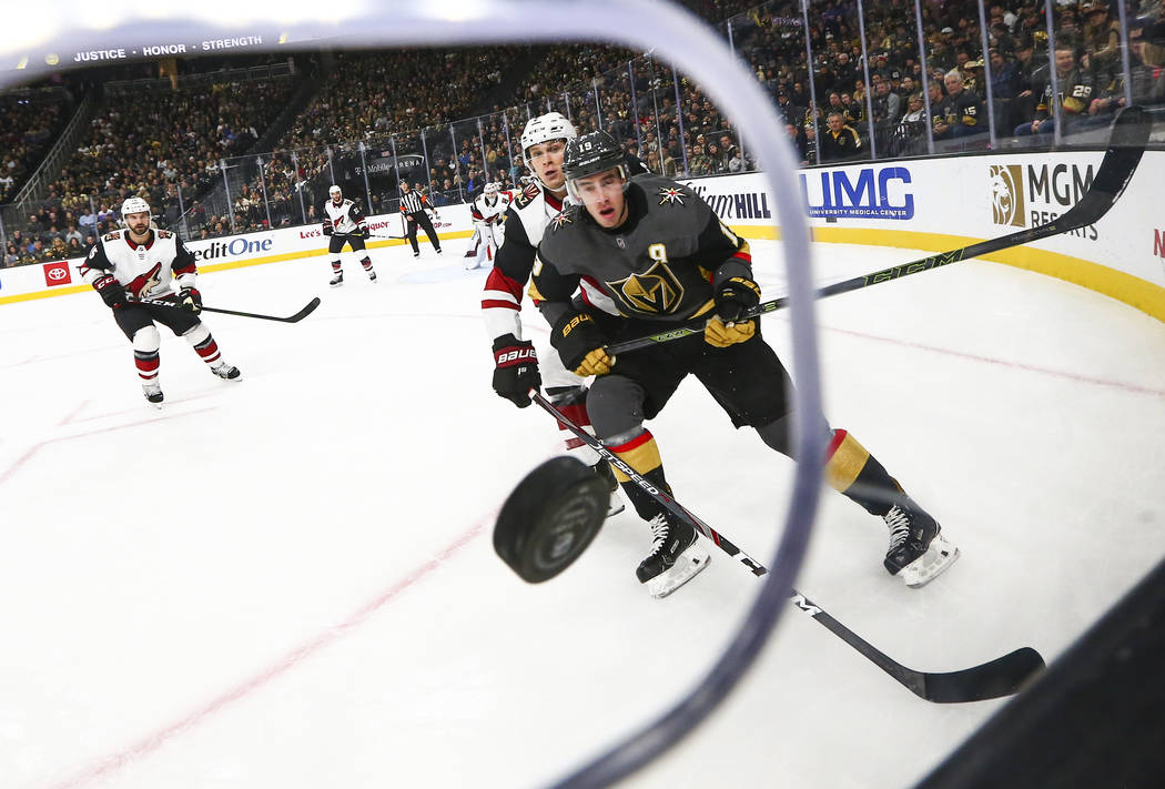 Golden Knights' Reilly Smith (19) and Arizona Coyotes' Jakob Chychrun (6) watch the puck fly to ...
