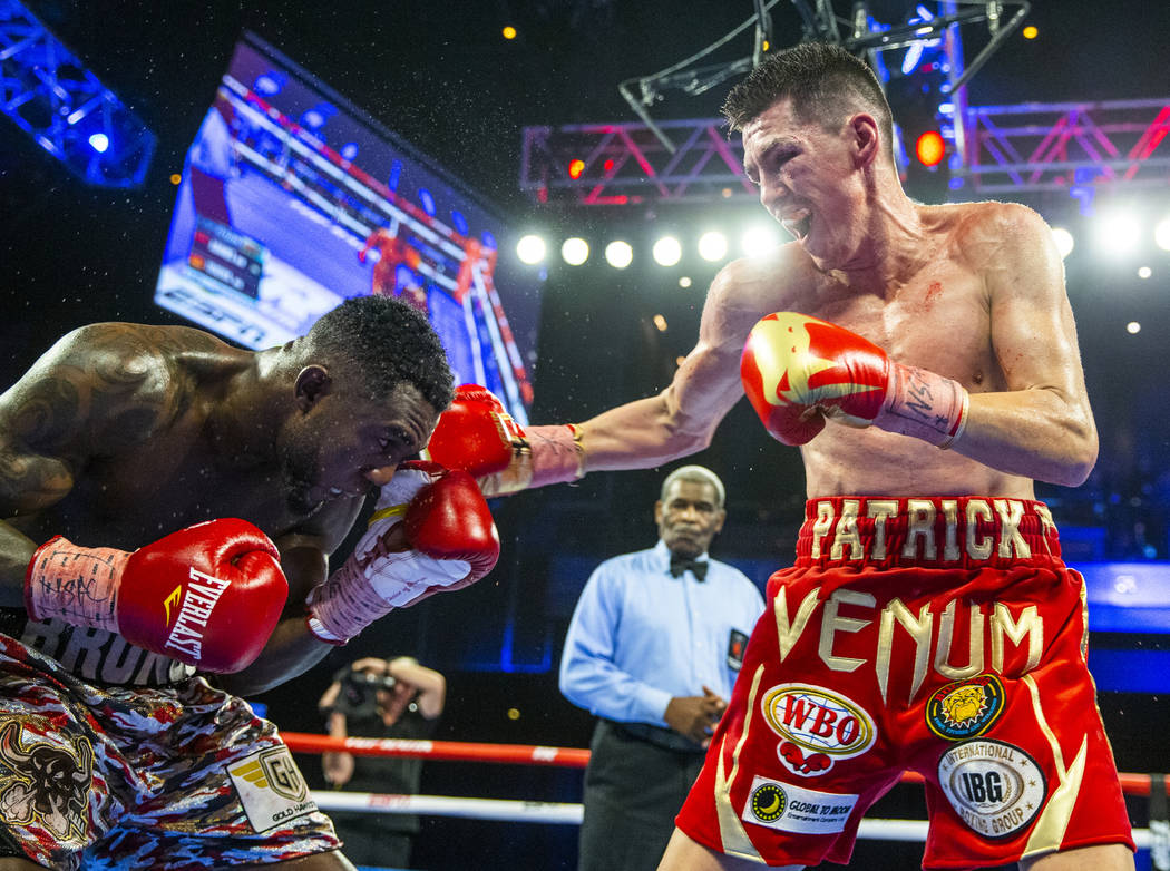 Carlos Adames, left, takes a punch from Patrick Teixeira during round 11 in their super welterw ...