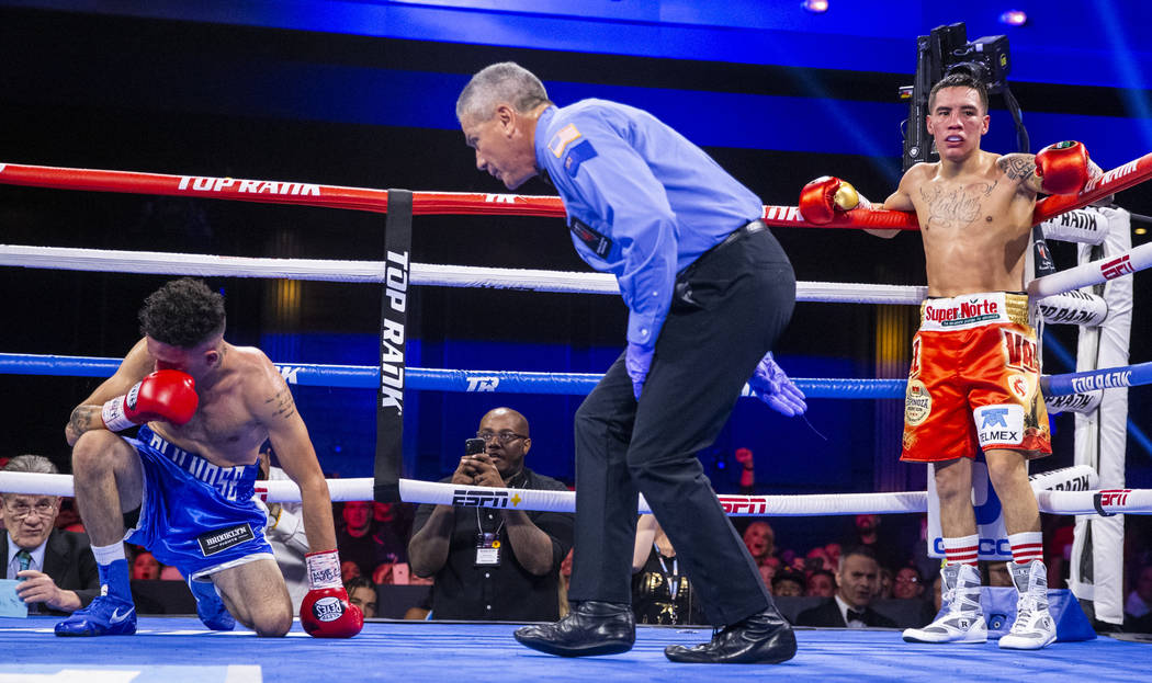 Adam Lopez, left, is checked on by the referee as Oscar Valdez waits in the corner during a kno ...