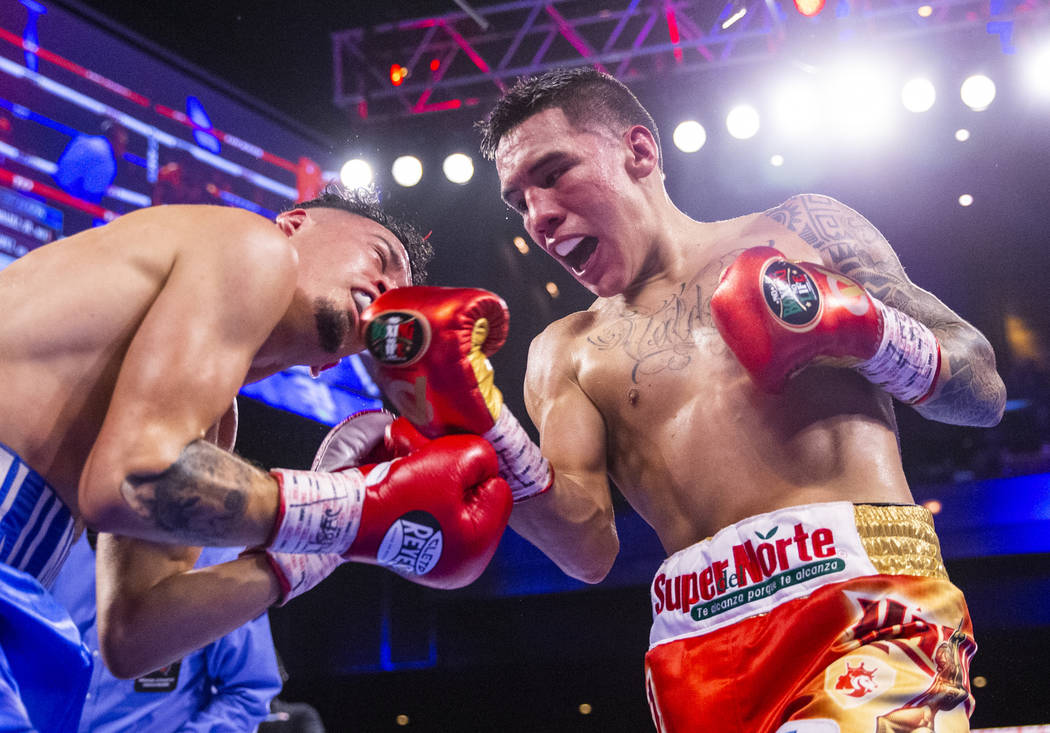 Adam Lopez, left, takes a right to the chin by Oscar Valdez during round 7 of their WBC super f ...