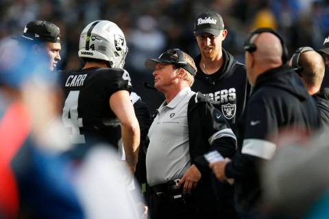 Oakland Raiders head coach Jon Gruden, center, talks with quarterback Derek Carr (4) during the ...