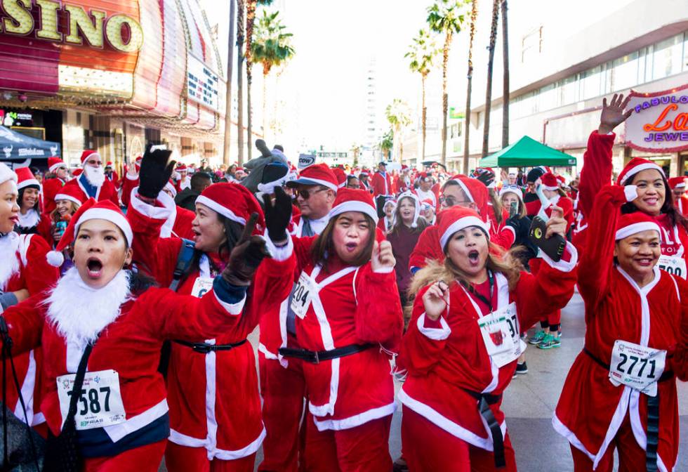 Santas dance during the pre-entertainment on the Third Street Stage at Fremont Street Experienc ...