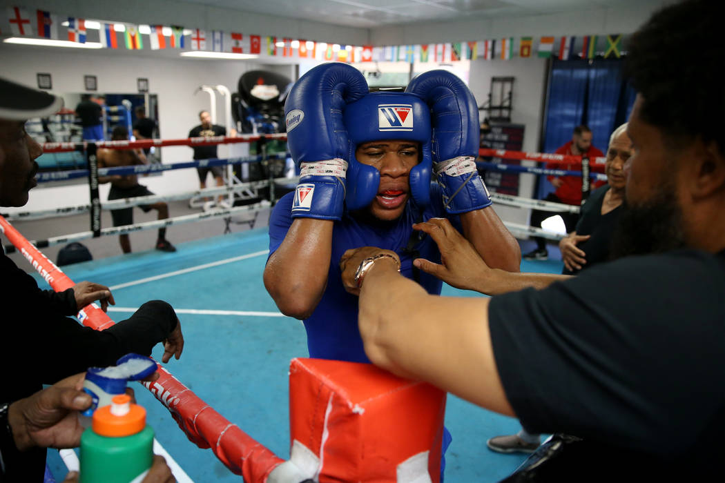 Boxer Devin Haney, center, adjust his headgear with help from his father and trainer William &q ...