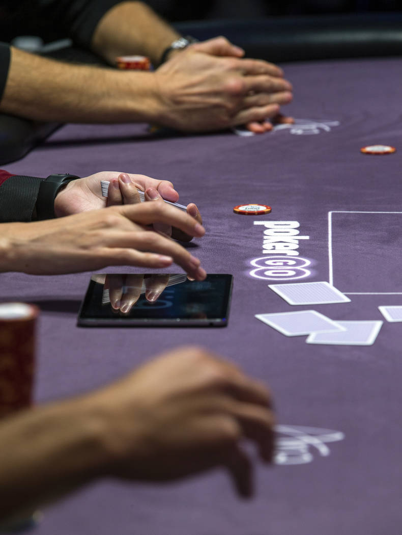 A dealer, center, keeps the playing time on a side table during the Poker Masters 2019 broadcas ...