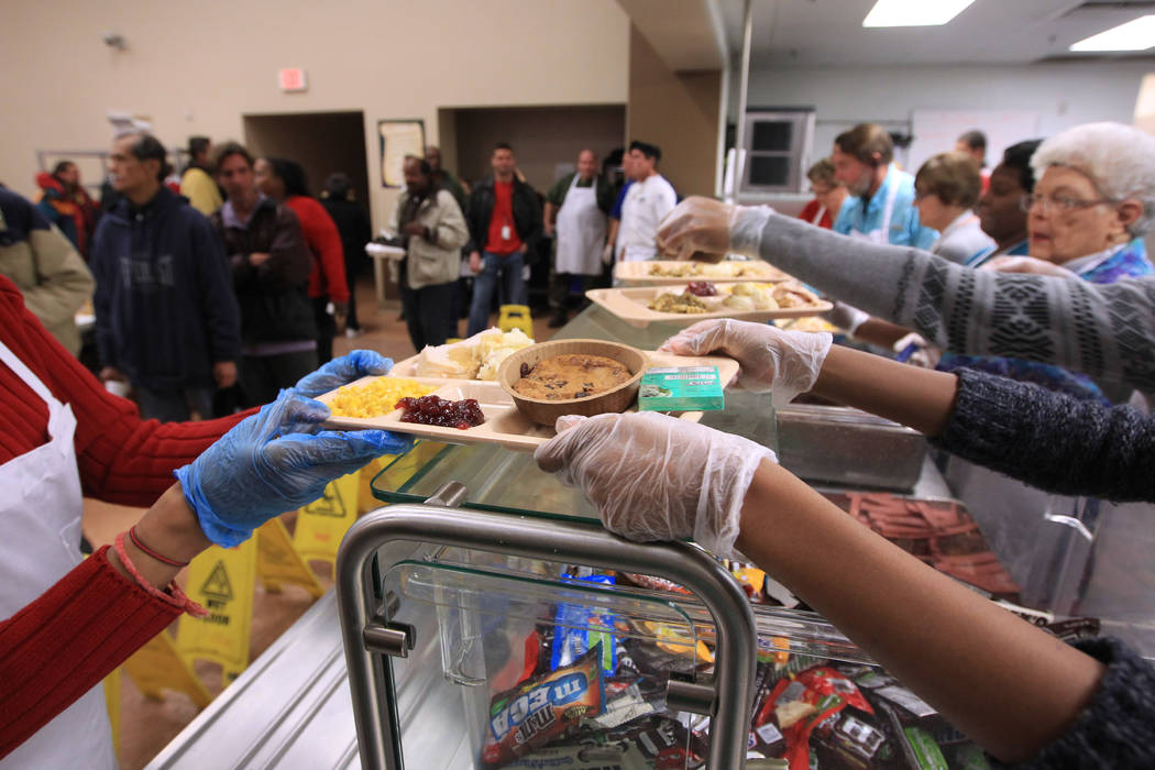 Volunteers serve up trays of turkey and all the trimmings during the Christmas meal at the Las ...