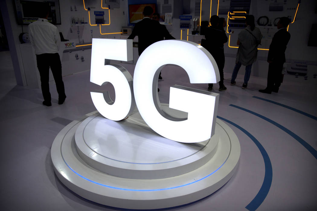 Visitors stand near a 5G logo at a display the PT Expo in Beijing in 2018. (AP Photo/Mark Schie ...