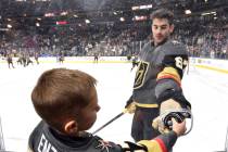 Vegas Golden Knights left wing Max Pacioretty hands a puck though a photographer's hole to a yo ...