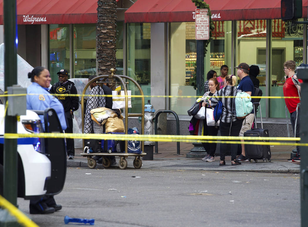 People wait with their luggage to leave the area on Canal Street next to Bourbon Street near th ...