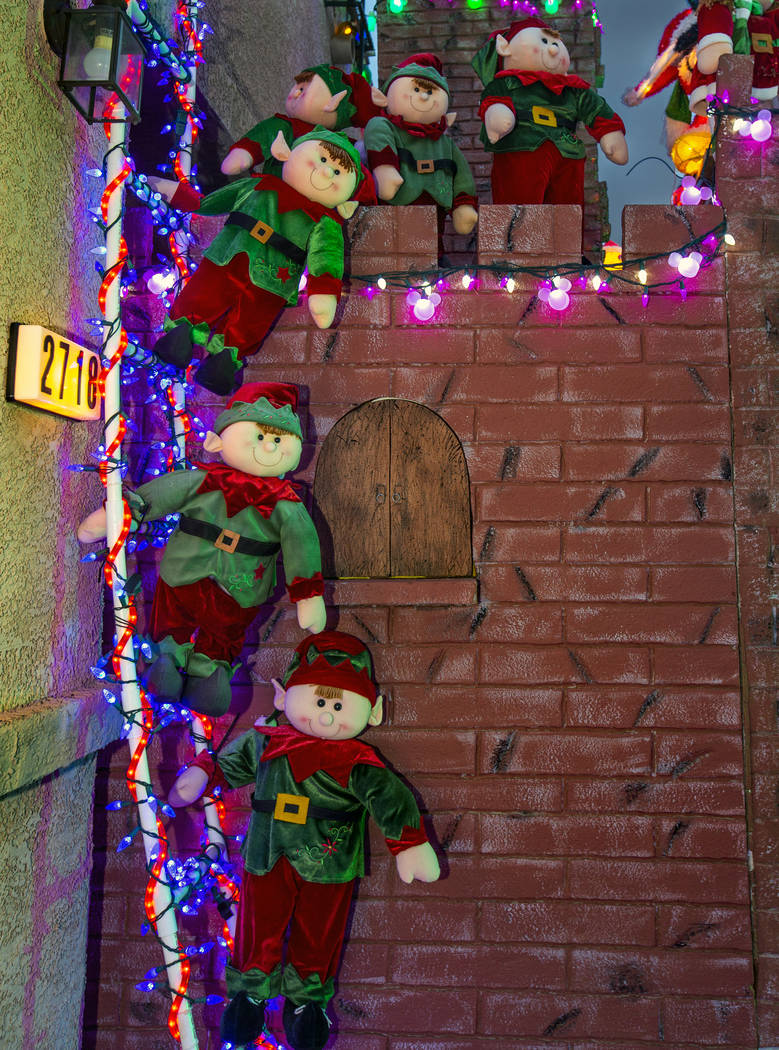 A group of elves on a ladder as part of the holiday lights display in the yard of Maria Acosta ...