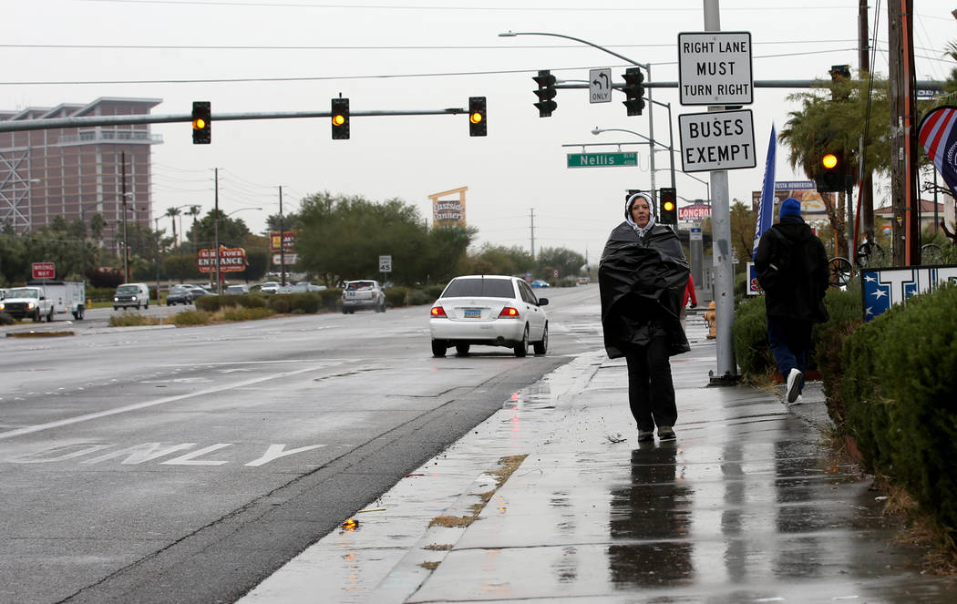 Penny Curiel stays dry under a plastic bag on Boulder Highway at Nellis Boulevard in Las Vegas ...