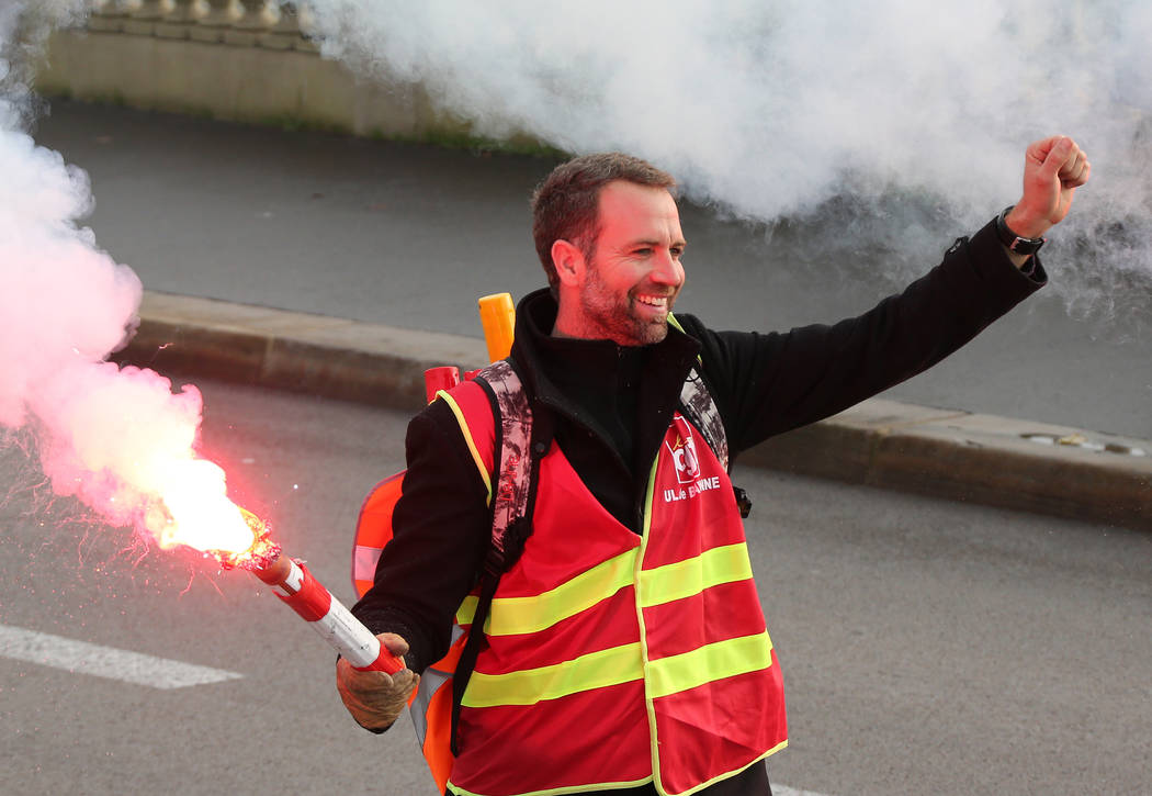 A demonstrator walks on with raised fist in Bayonne, southwestern France, Thursday, Dec.5, 2019 ...