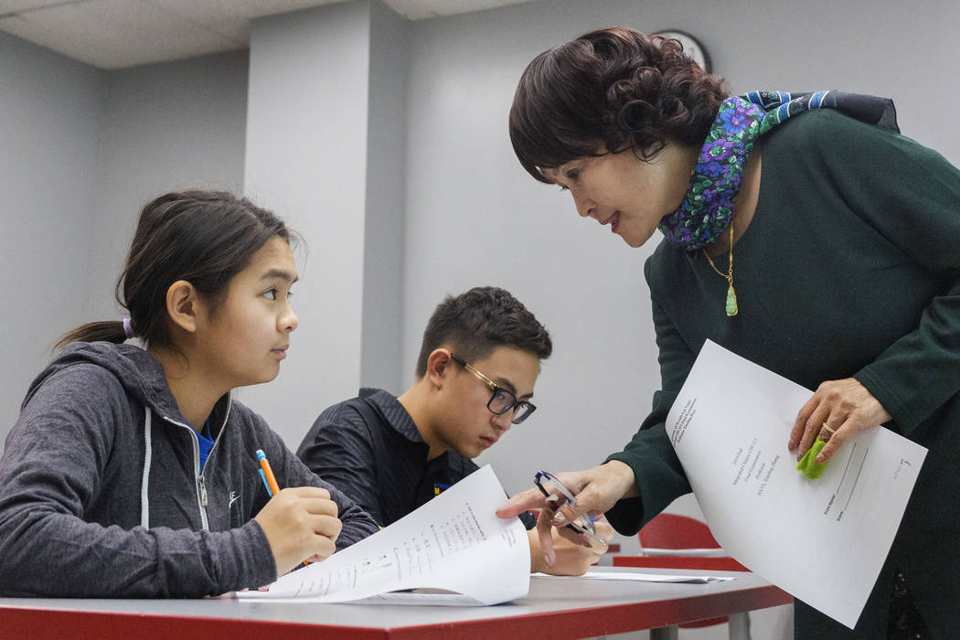 Shenmei Wu, 13, left, listens to UNLV Chinese professor Xiaoling Hays, next to her brother Shen ...