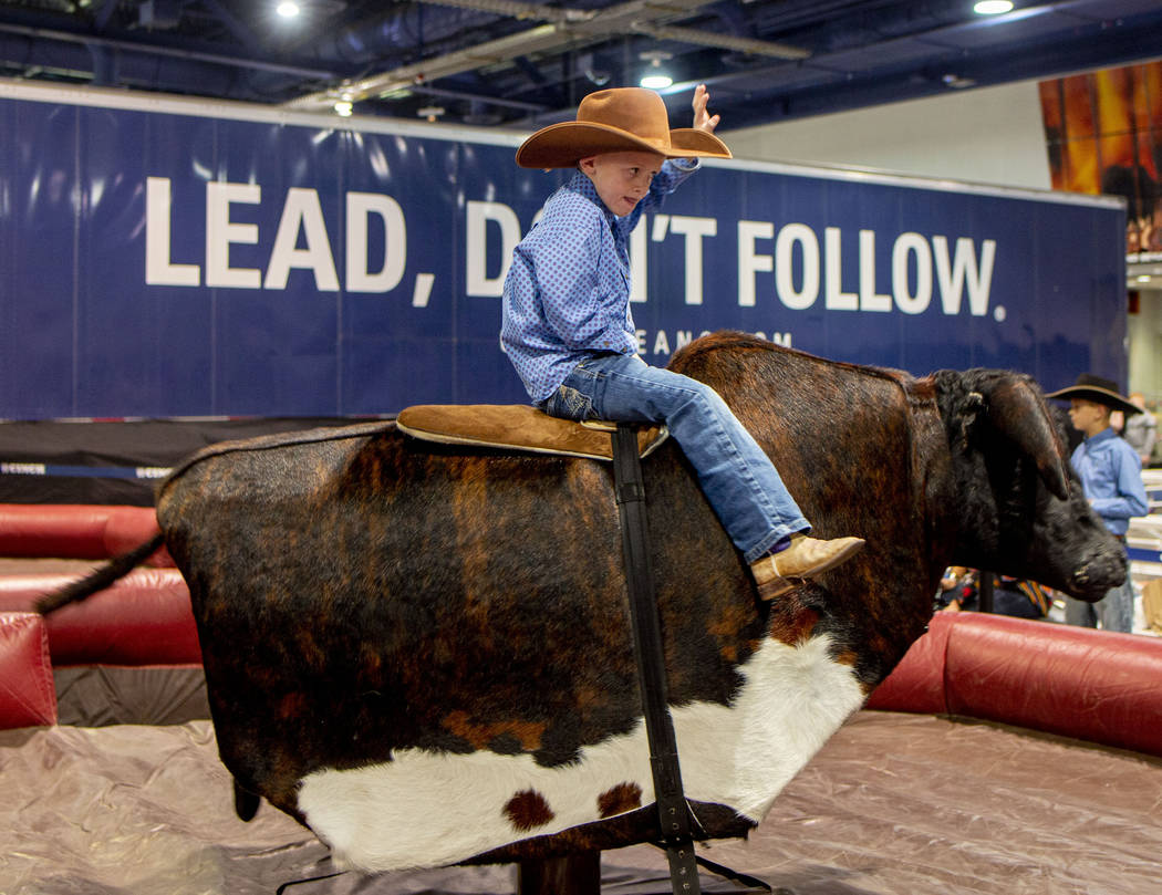 Riggin Osborne, 5, of Mountain View, Wyo., rides a mechanical bull at Cowboy Christmas at the L ...