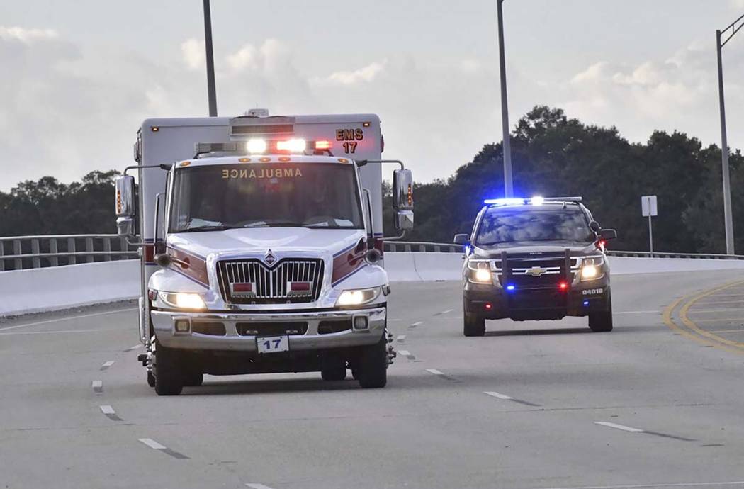 Police cars escort an ambulance after a shooter open fire inside the Pensacola Air Base, Friday ...