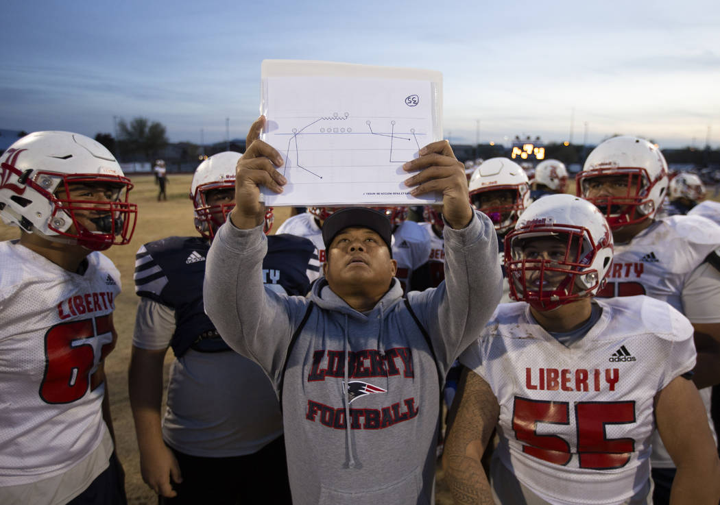 Liberty High School coach Al Tucay holds up a play for the team during football practice at Lib ...